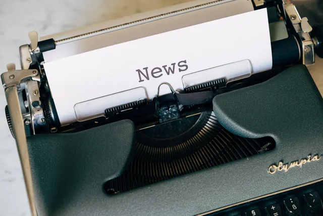 Close-up of a vintage Olympia typewriter with paper reading 'news'. Perfect for classic journalism themes. Opening a newsletter business: costs to expect and money to find